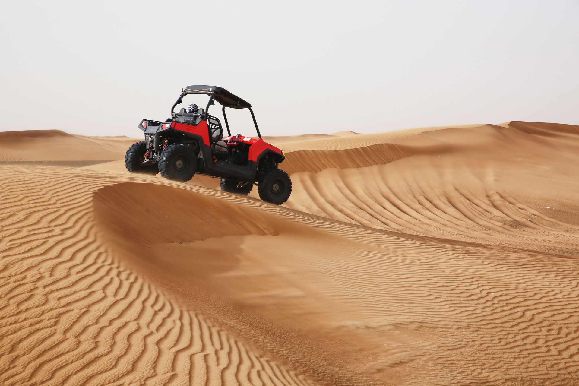 Off-road SUV vehicle speeding through sand dunes in the Arabian desert.