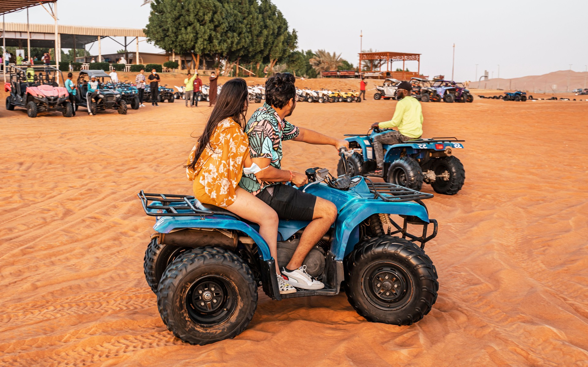 November 18, 2021 UAE, Dubai - Happy quad bikers driving in sand dunes. Young active couple in outdoor activity driving quad ATV in the Desert, Dubai, United Arab Emirates