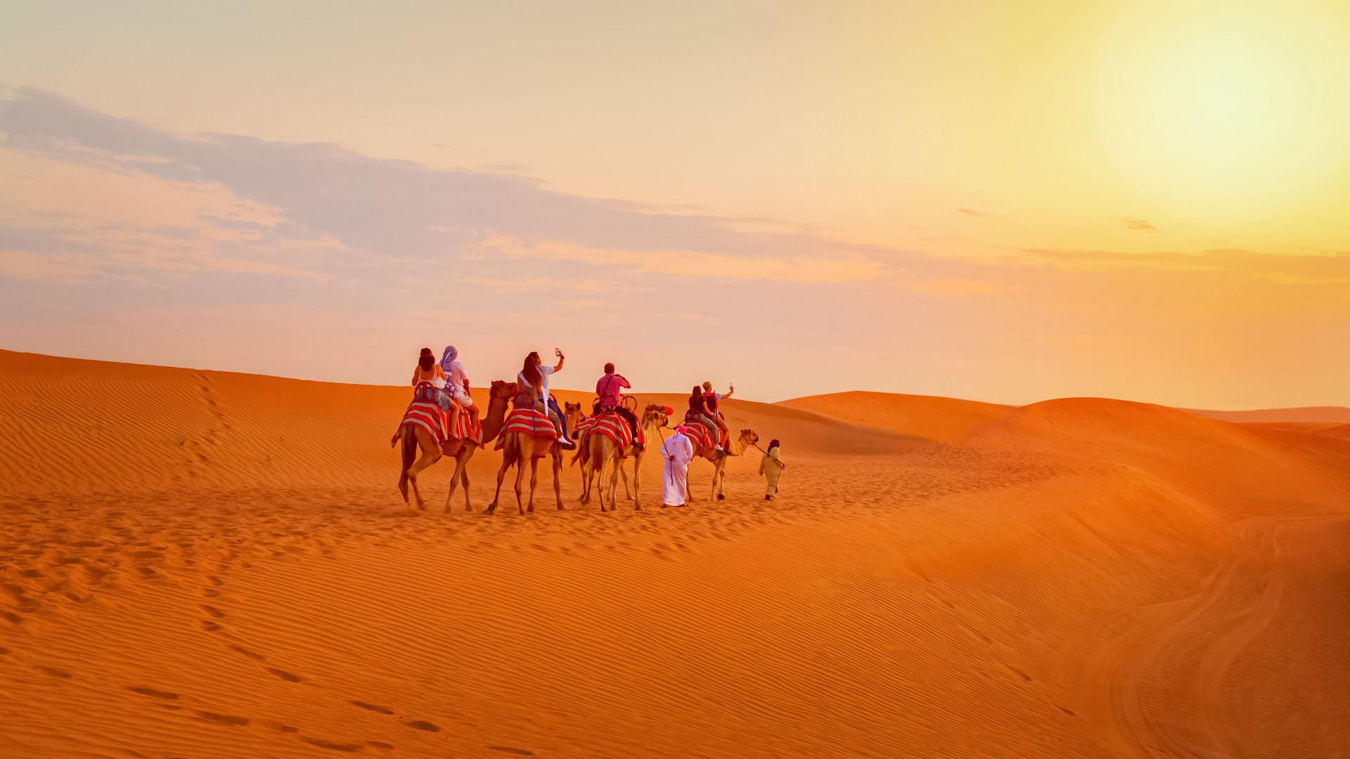 Camel caravan with tourists on desert safari adventure