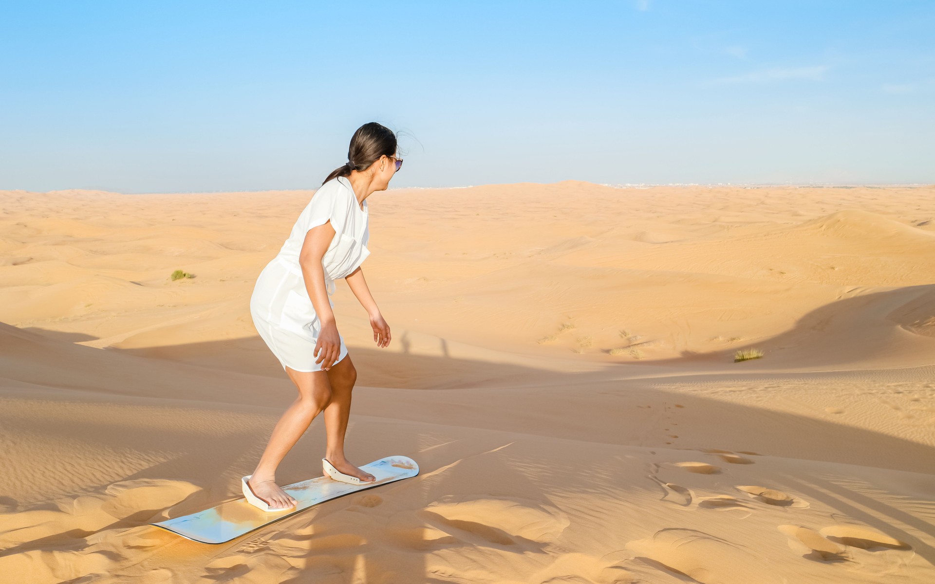 Young women sand surfing at the sand dunes of Dubai United Arab Emirates