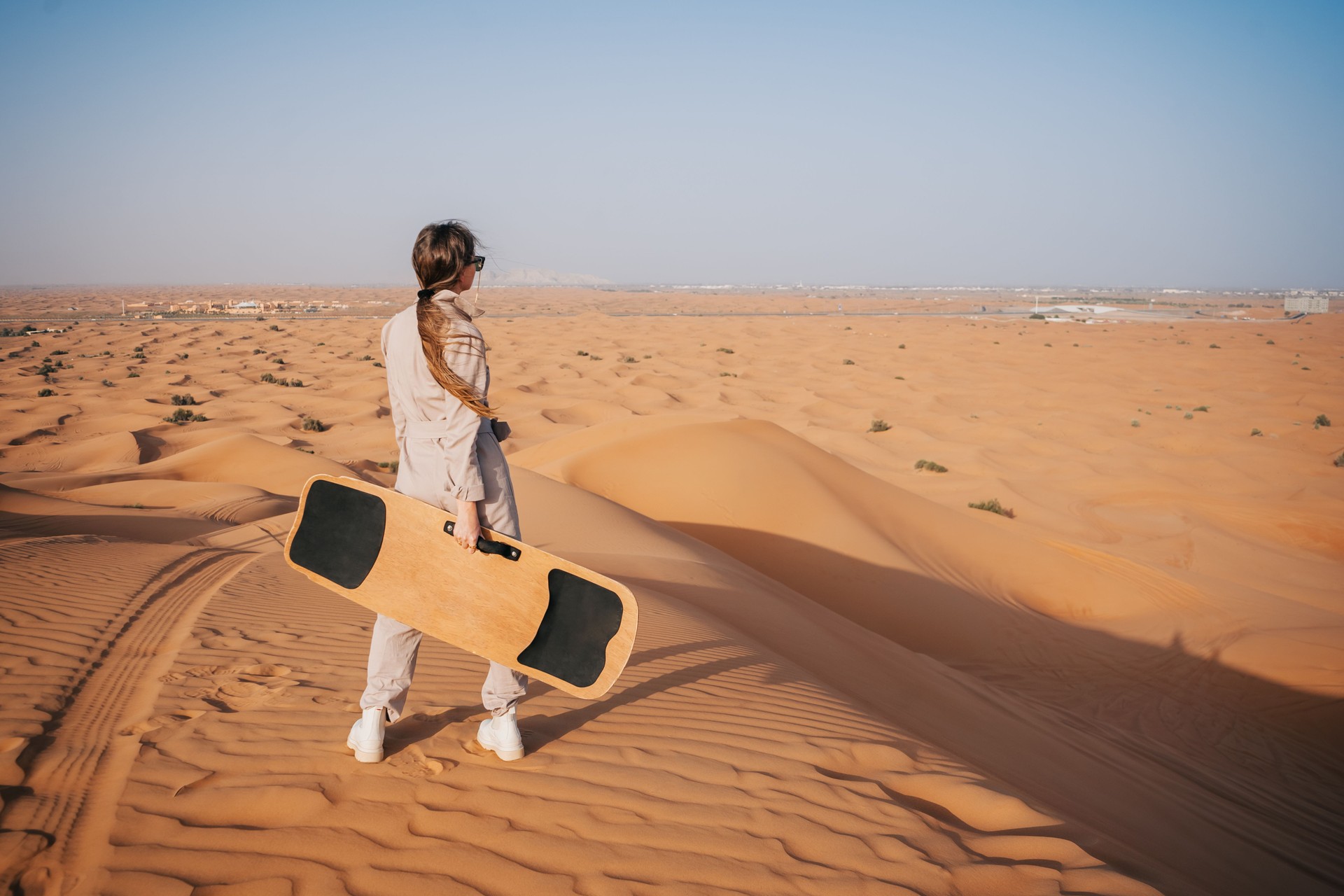 Woman with sandboard standing in the dunes